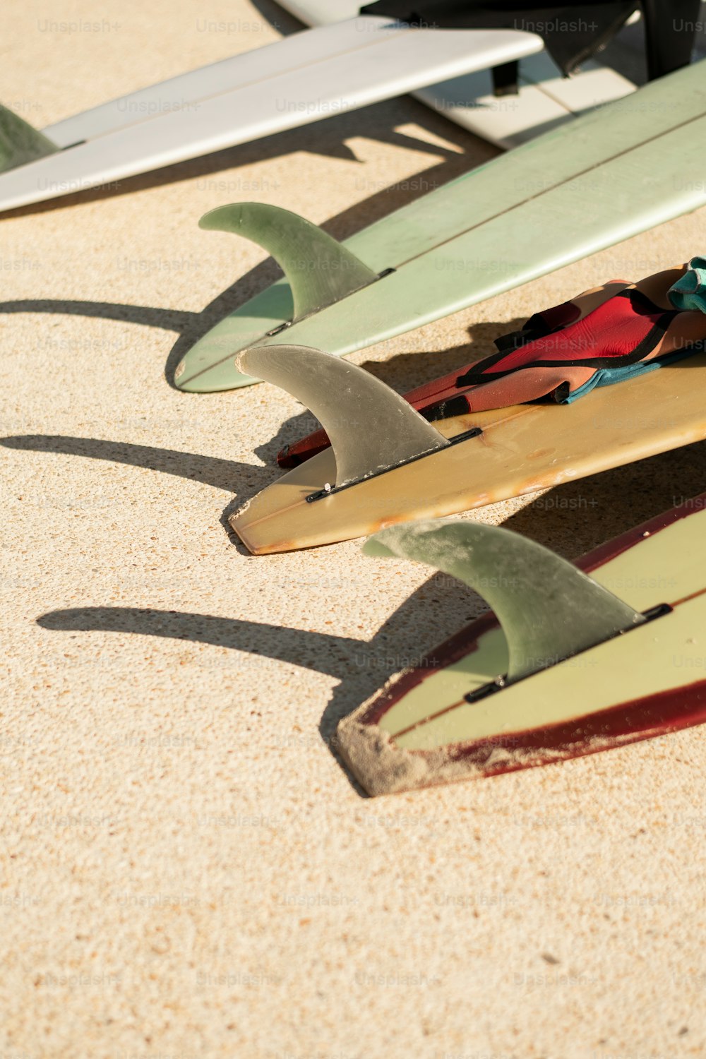 Un gruppo di tavole da surf sedute sulla cima di una spiaggia sabbiosa