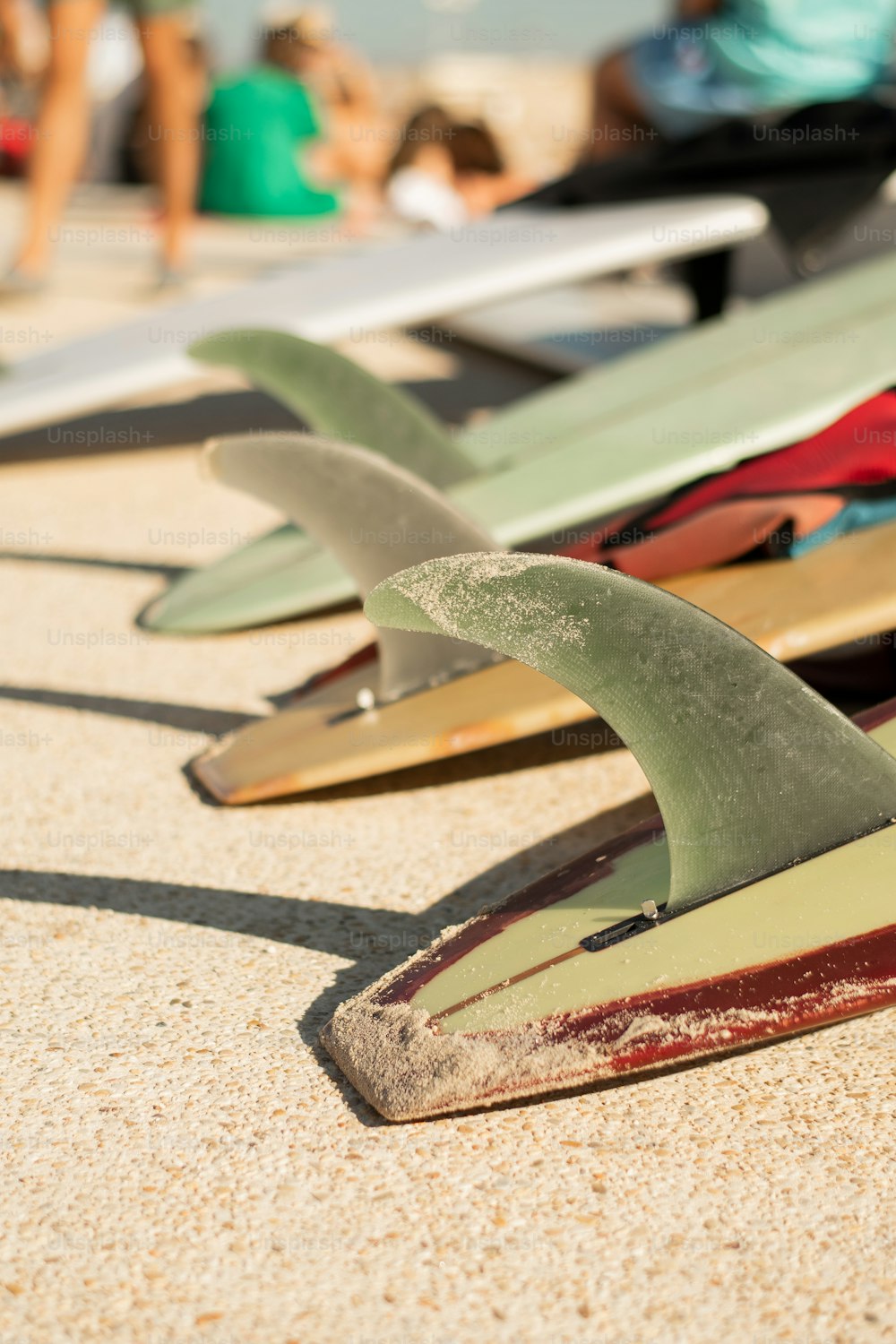 Una hilera de tablas de surf sentadas en la parte superior de una playa de arena