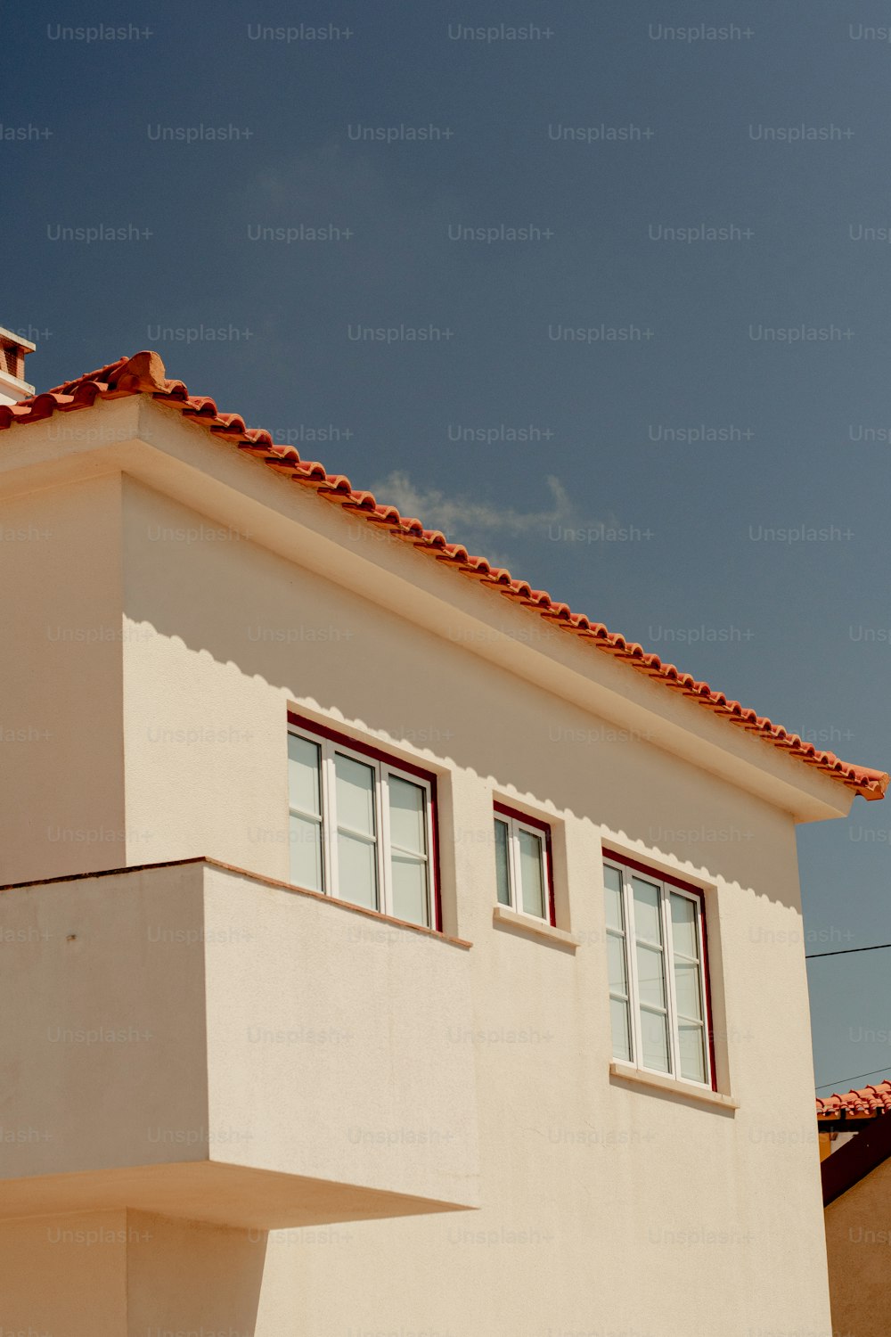 un edificio blanco con techo rojo y dos ventanas