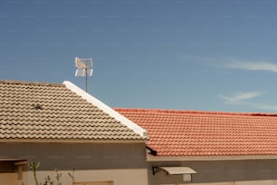 赤い瓦屋根とその上に風向計がある家