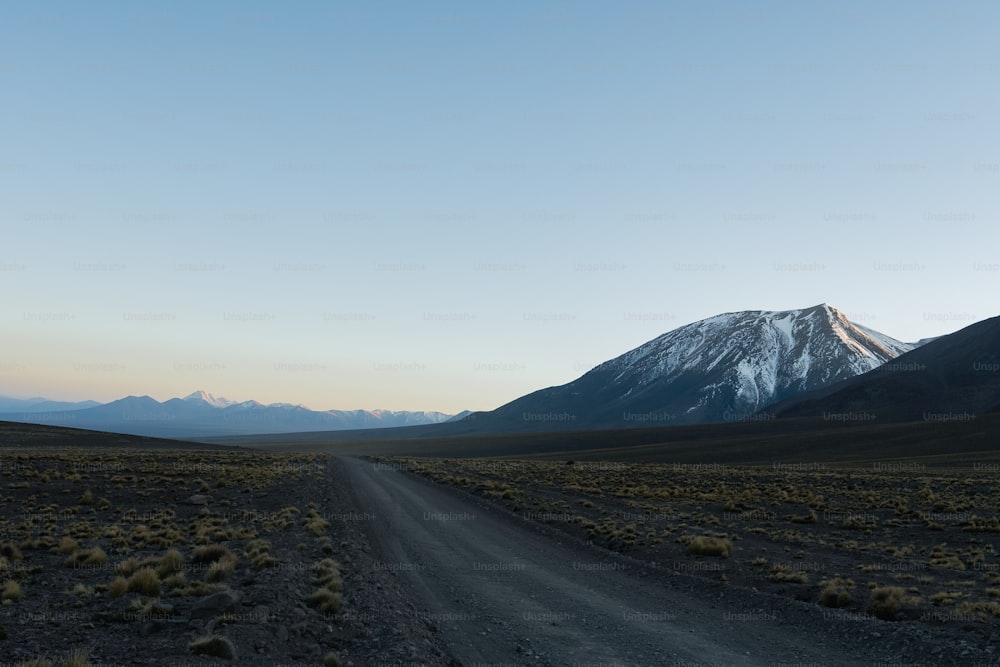 a dirt road with a mountain in the background