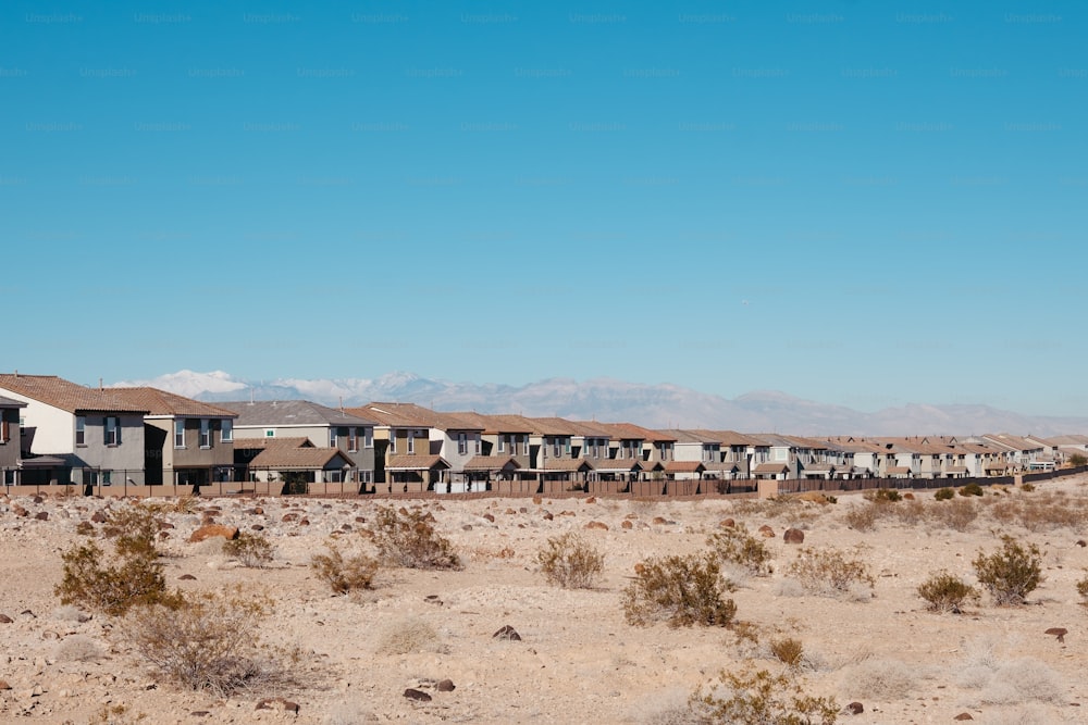 Une rangée de maisons dans le désert avec des montagnes en arrière-plan