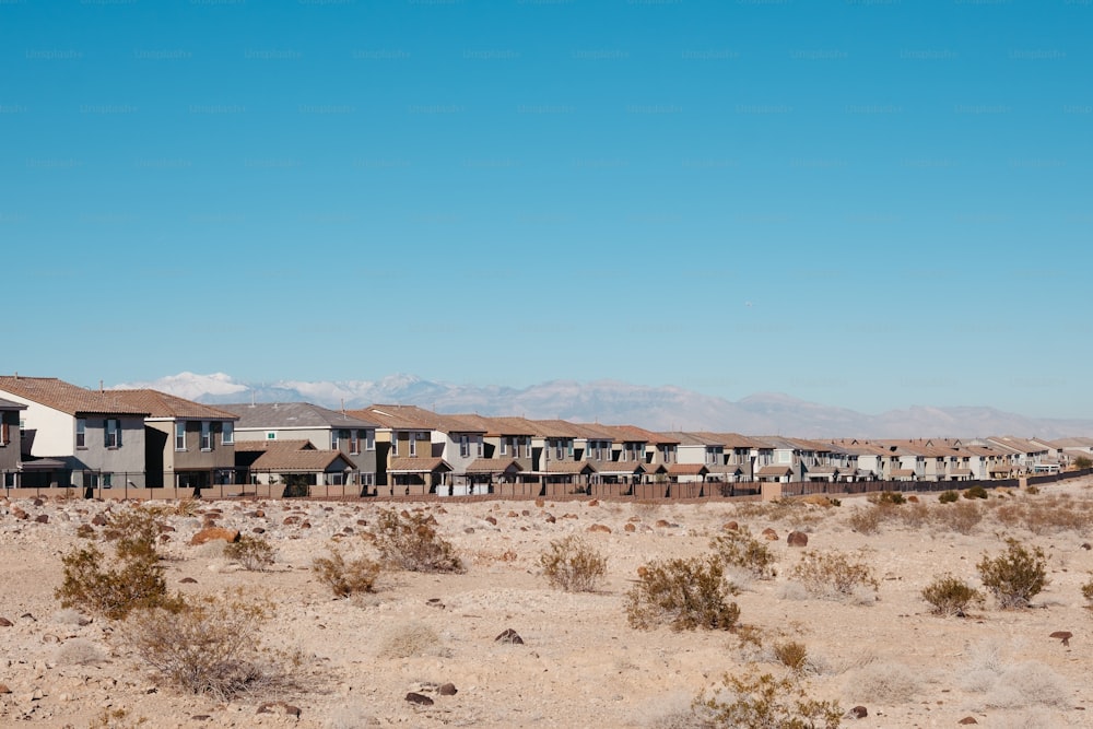 a row of houses in the desert with mountains in the background