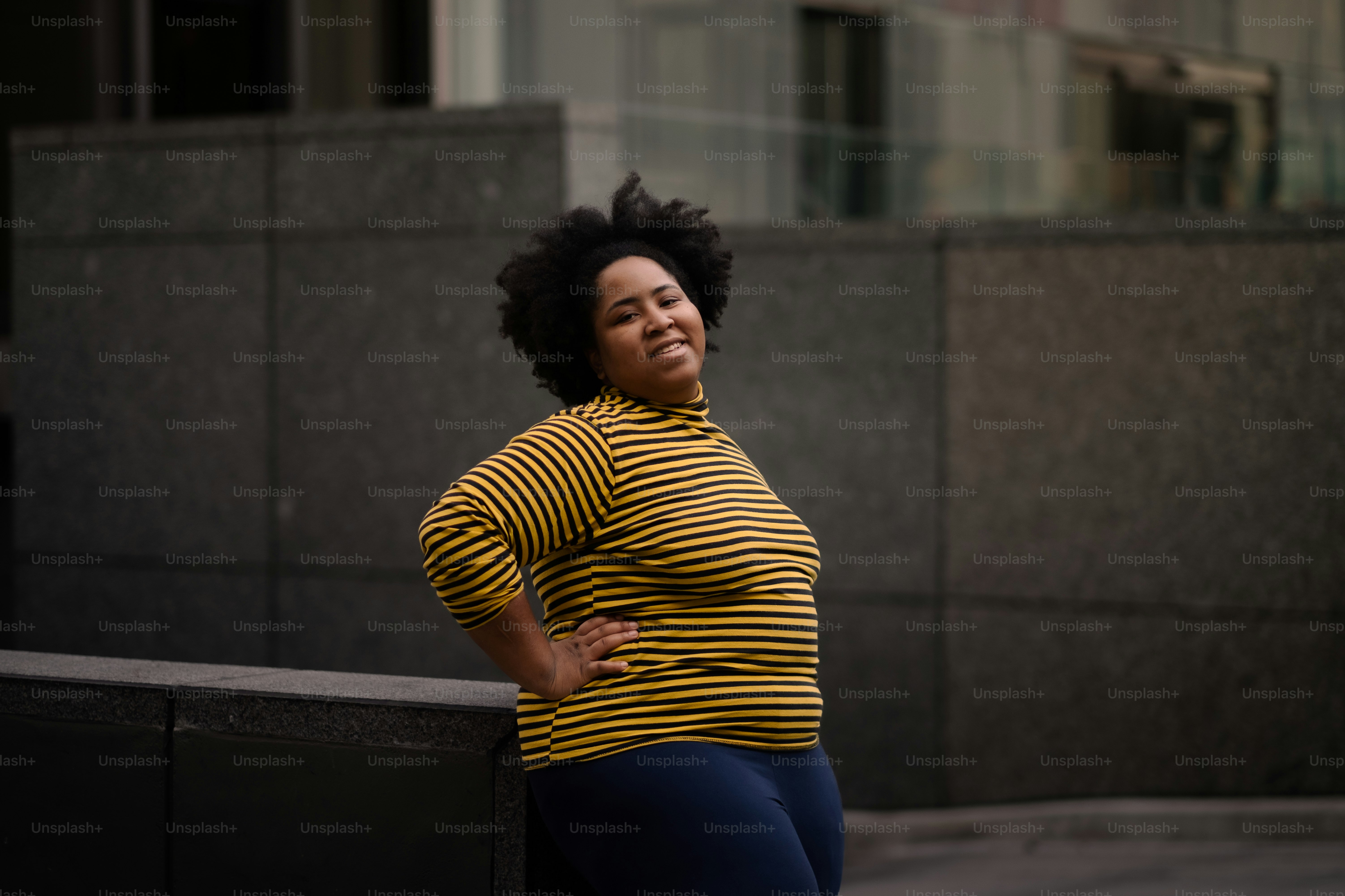 A woman leaning against a wall with her hands on her hips photo – Woman ...