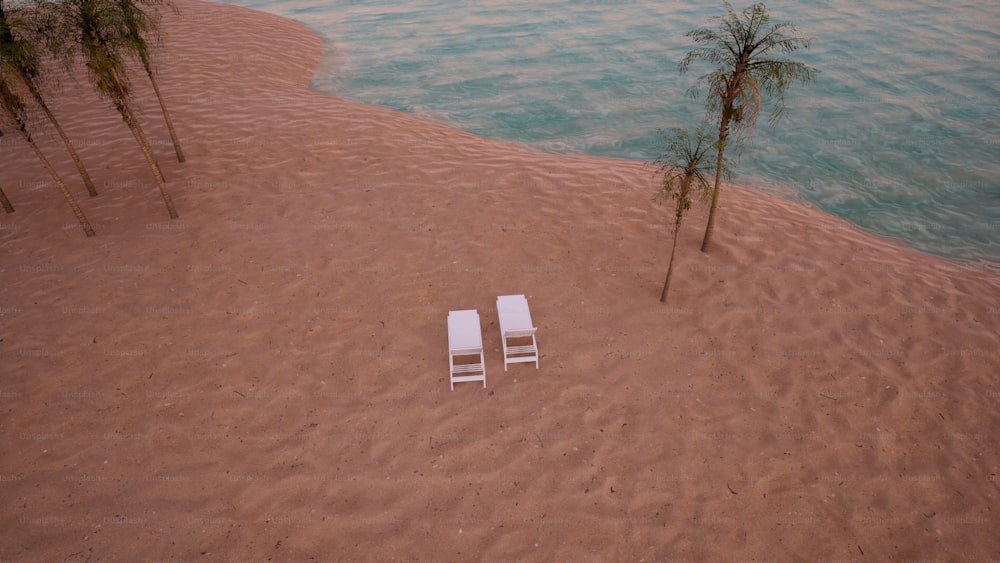two white lawn chairs sitting on top of a sandy beach