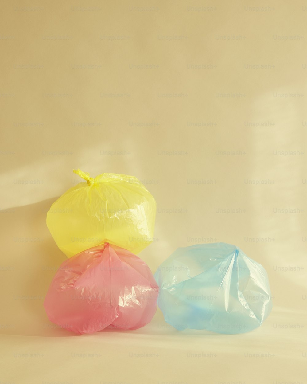 três sacos plásticos de cores diferentes em um fundo bege