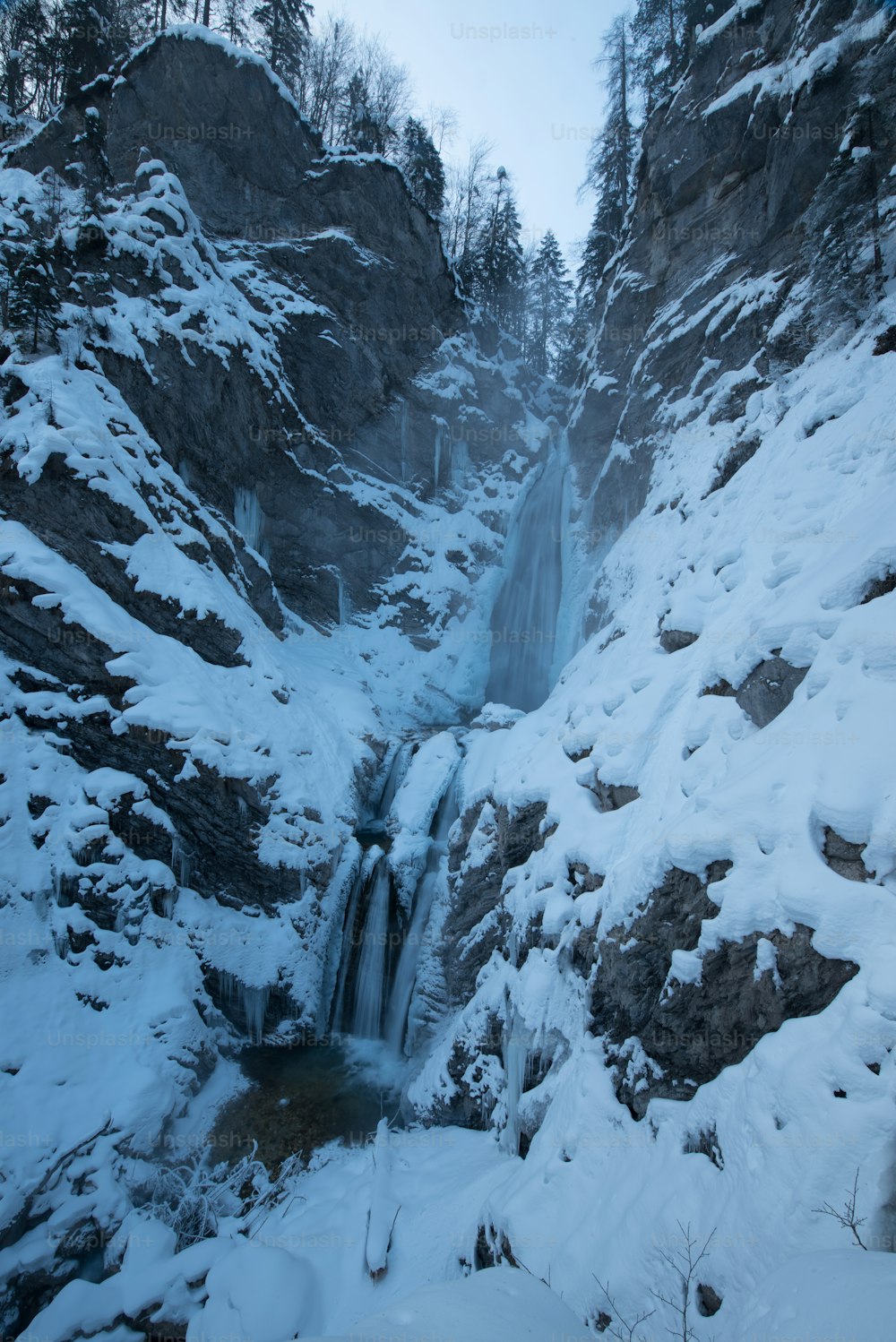 um lado da montanha coberto de neve com uma cachoeira