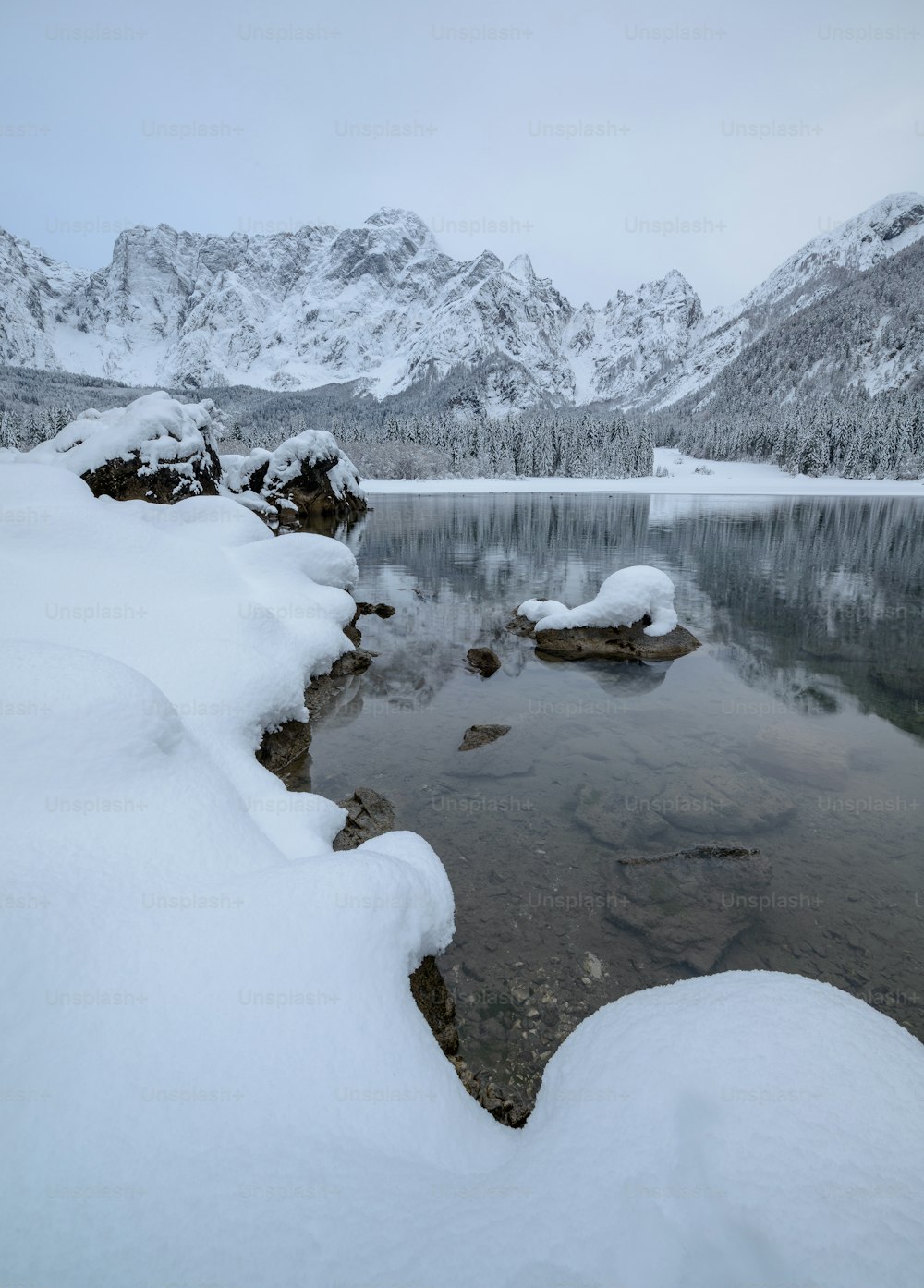 a lake surrounded by snow covered mountains