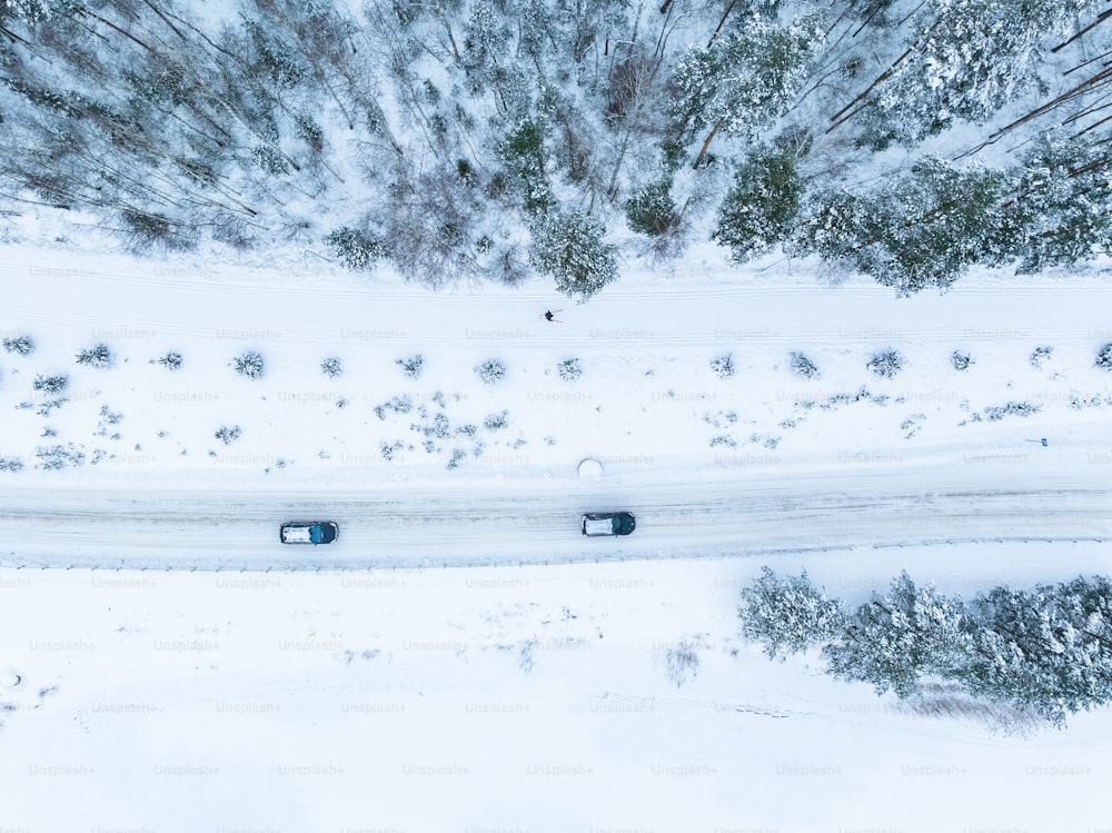 une vue aérienne de deux voitures roulant sur une route enneigée