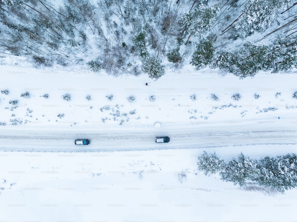 an aerial view of two cars driving down a snowy road