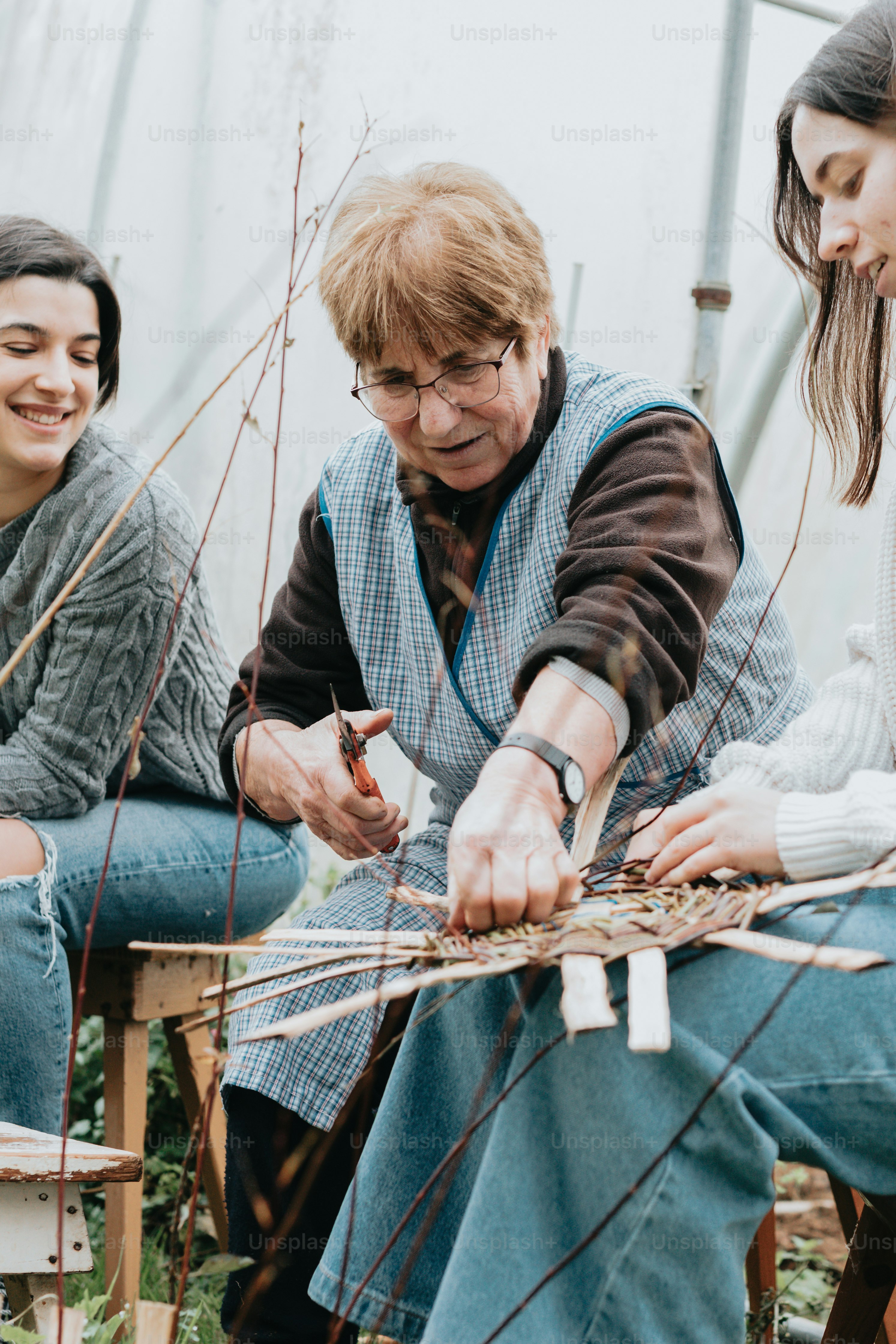 a woman sitting next to a woman who is working on a piece of art