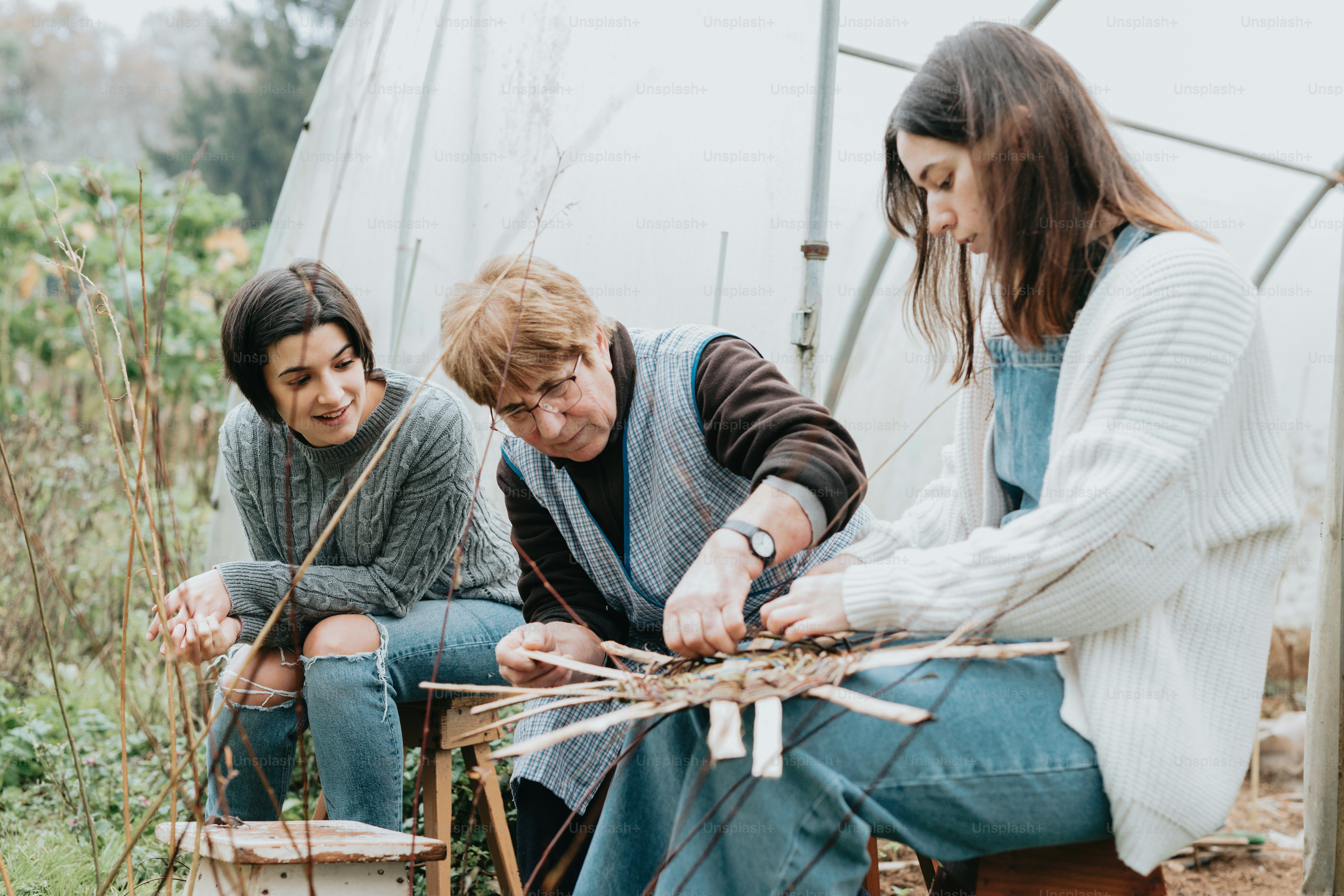 two women and a man are working in a garden