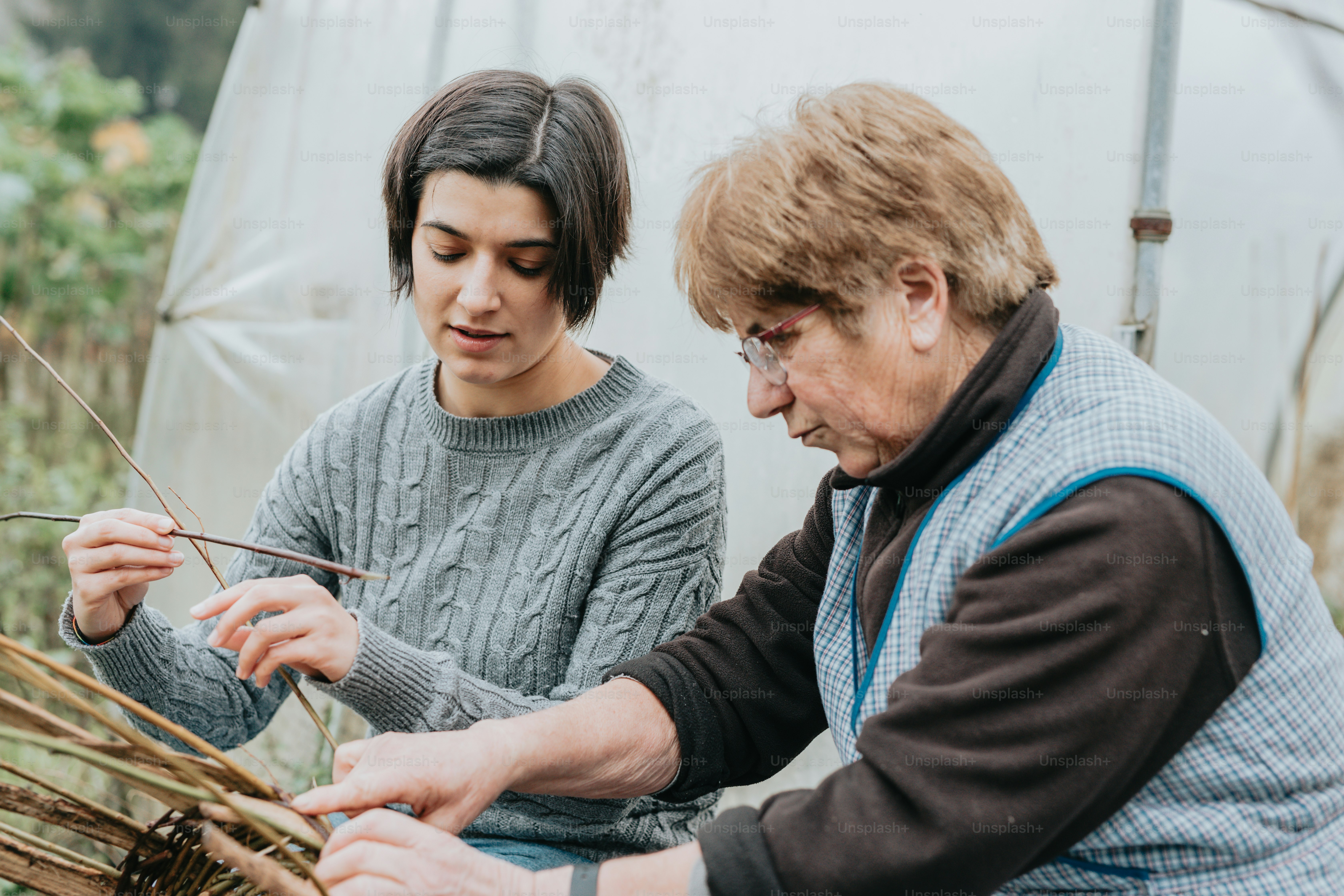 a man and a woman working on a basket