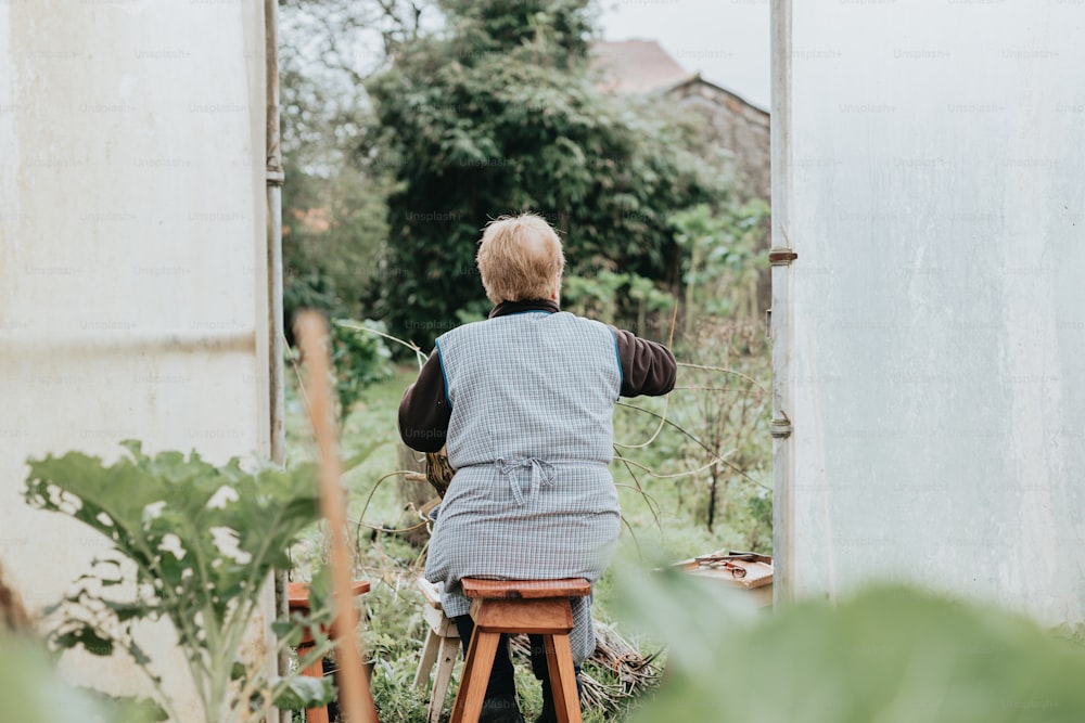 a person sitting on a stool in a garden