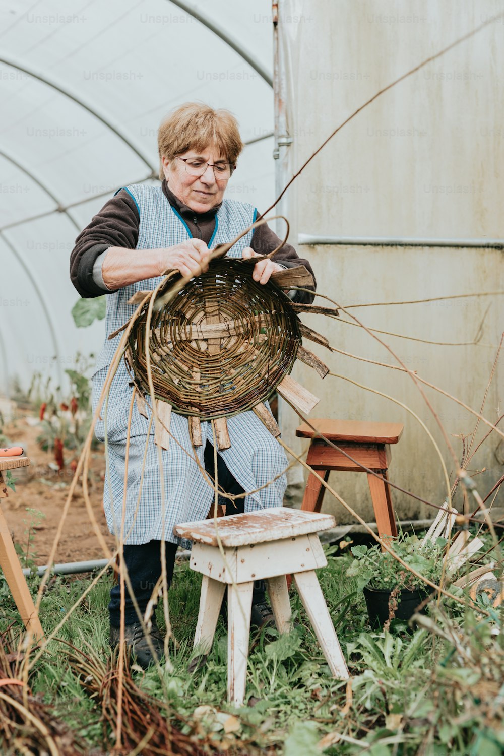 a woman in a greenhouse working on a wicker basket