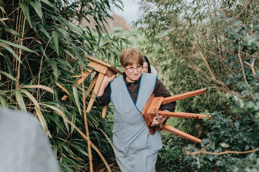 uma mulher andando através de uma floresta carregando um objeto de madeira