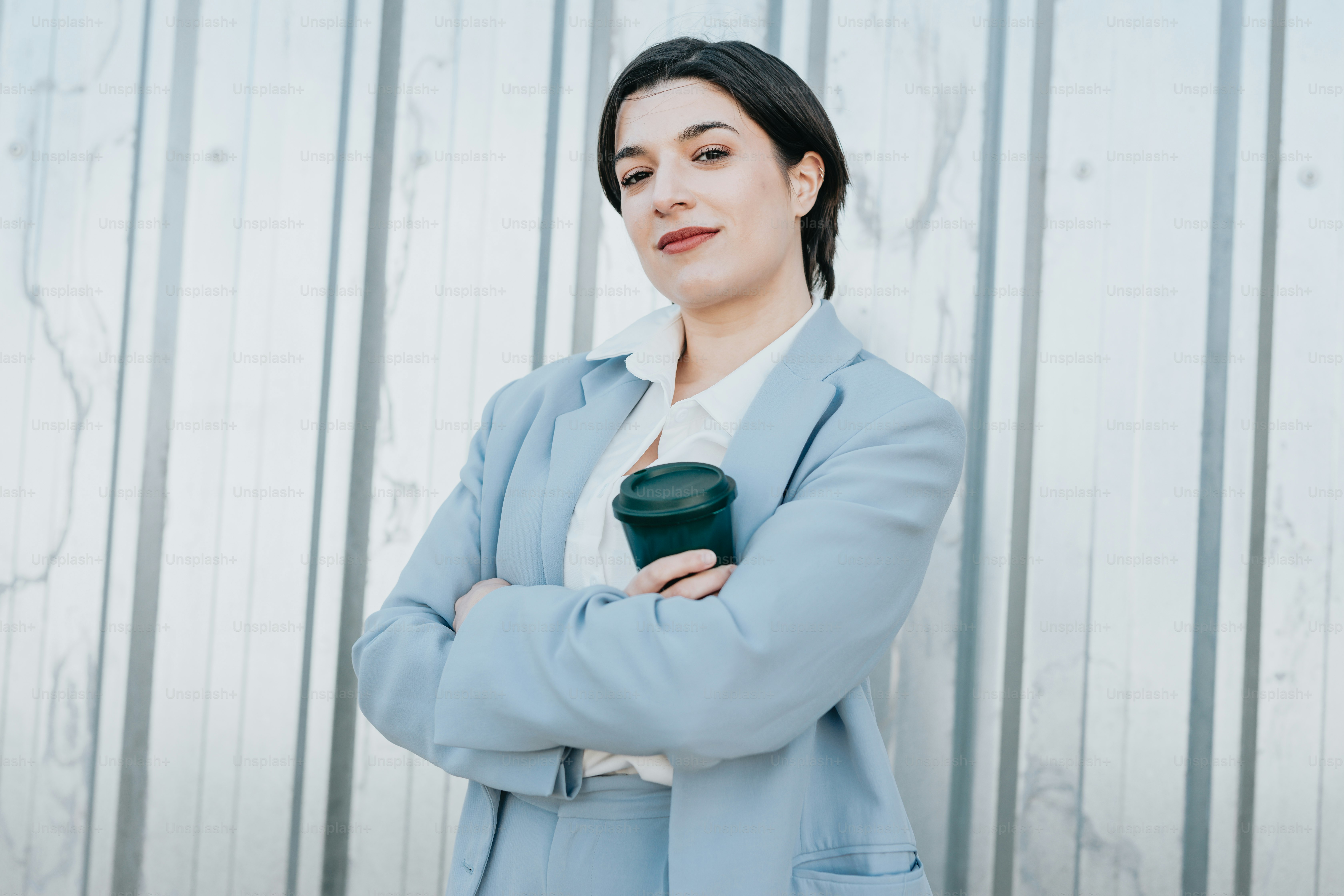 A woman standing with her arms crossed in front of a wall photo ...