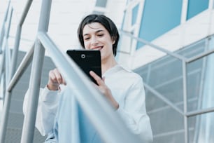 a woman in a white shirt is holding a tablet