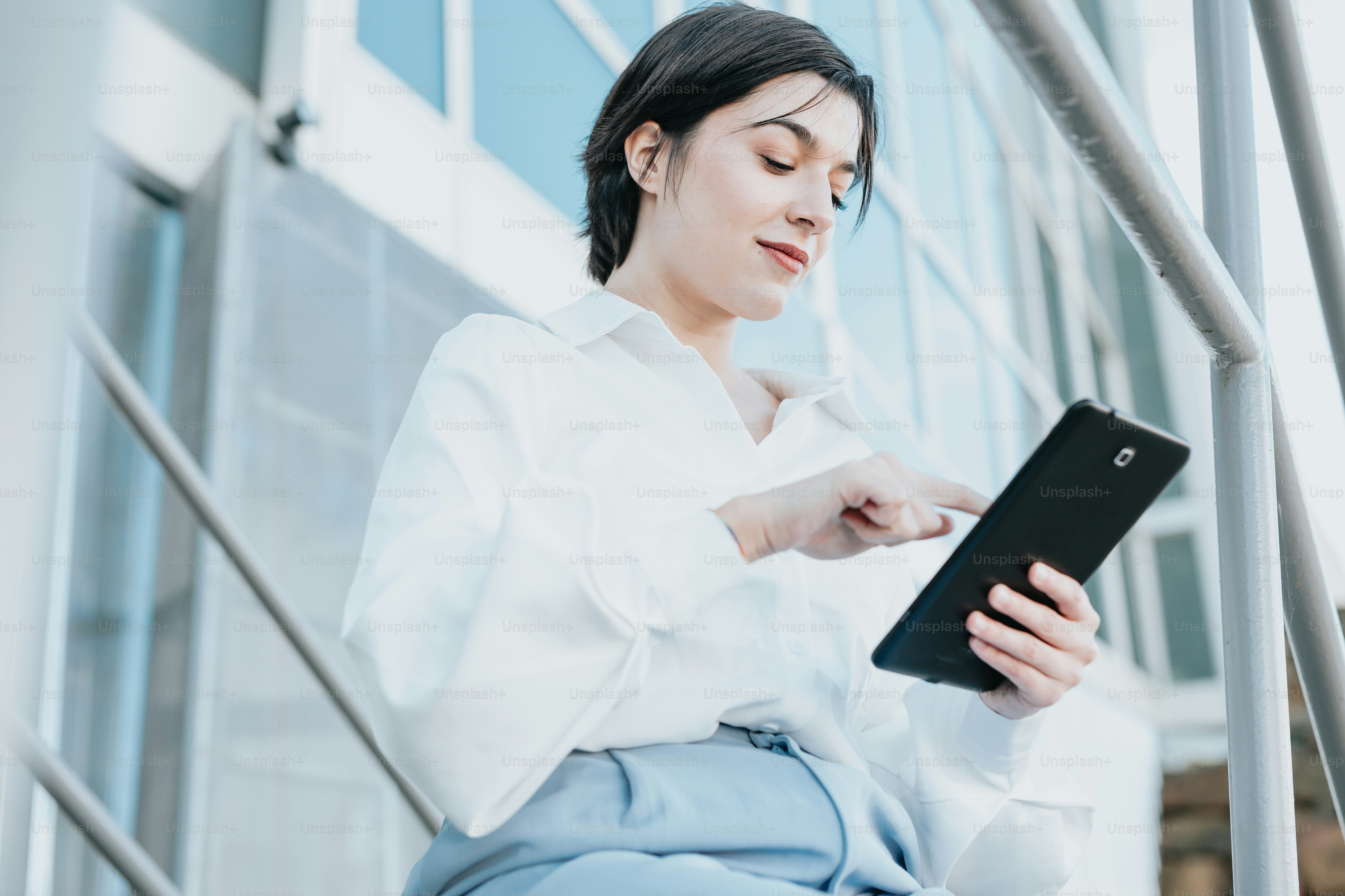 Une femme en chemise blanche tient une tablette