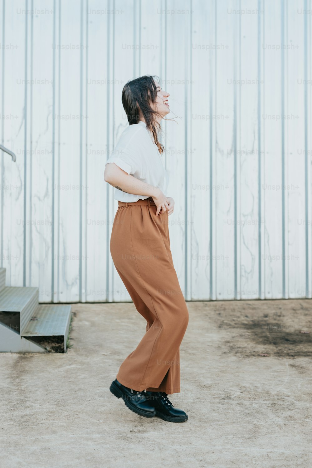 a woman in a white shirt and brown pants