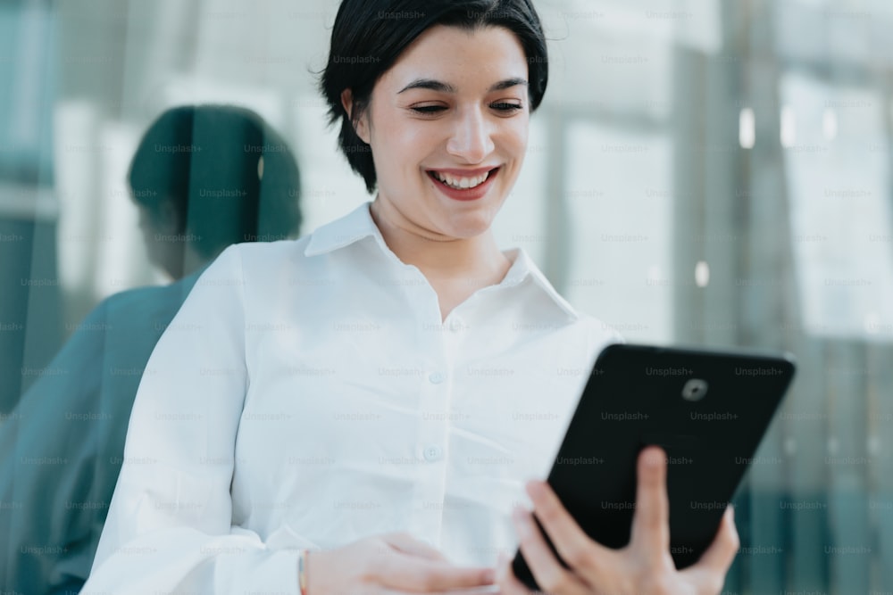 Une femme en chemise blanche tient une tablette