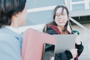 Una mujer sosteniendo una carpeta y sonriendo a otra mujer