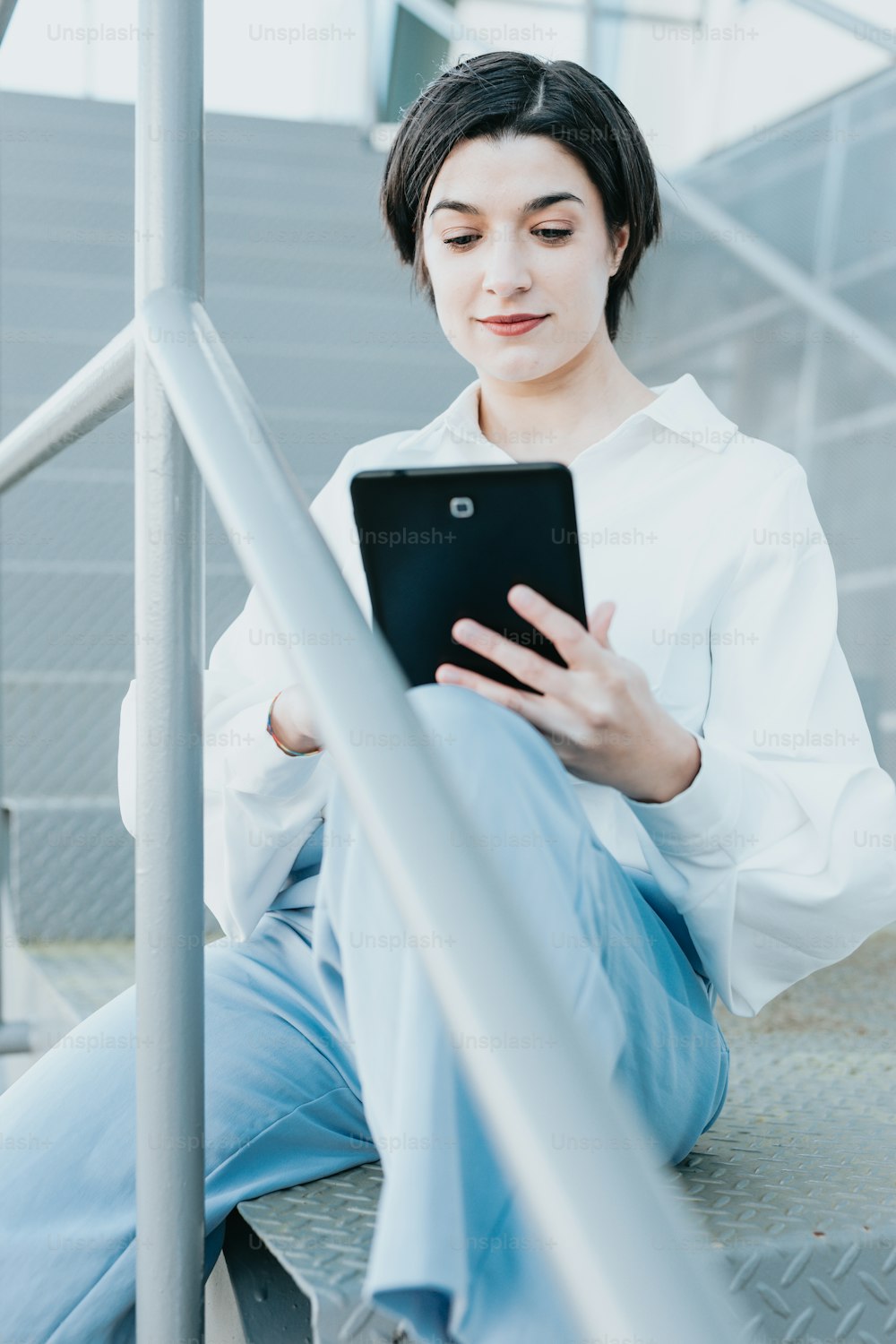 a woman sitting on the steps using a tablet