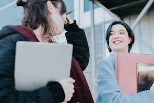 a woman holding a laptop computer next to another woman