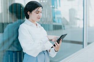 a woman standing in front of a window holding a tablet