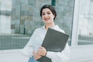 a woman in a white shirt is holding a folder