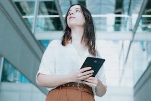 a woman in a white shirt is holding a tablet