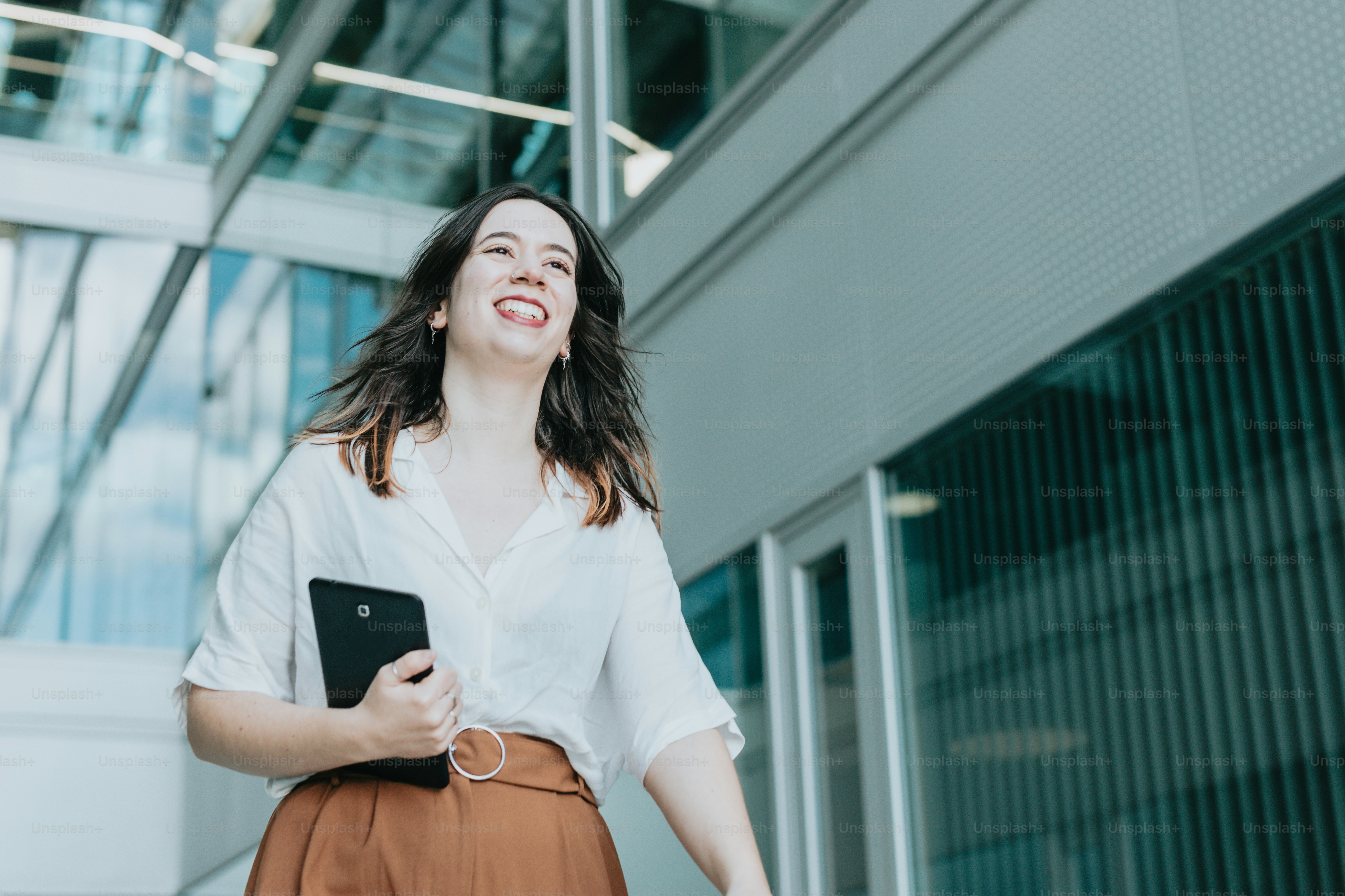 タブレットを持つ白いシャツと茶色のスカートを着た女性
