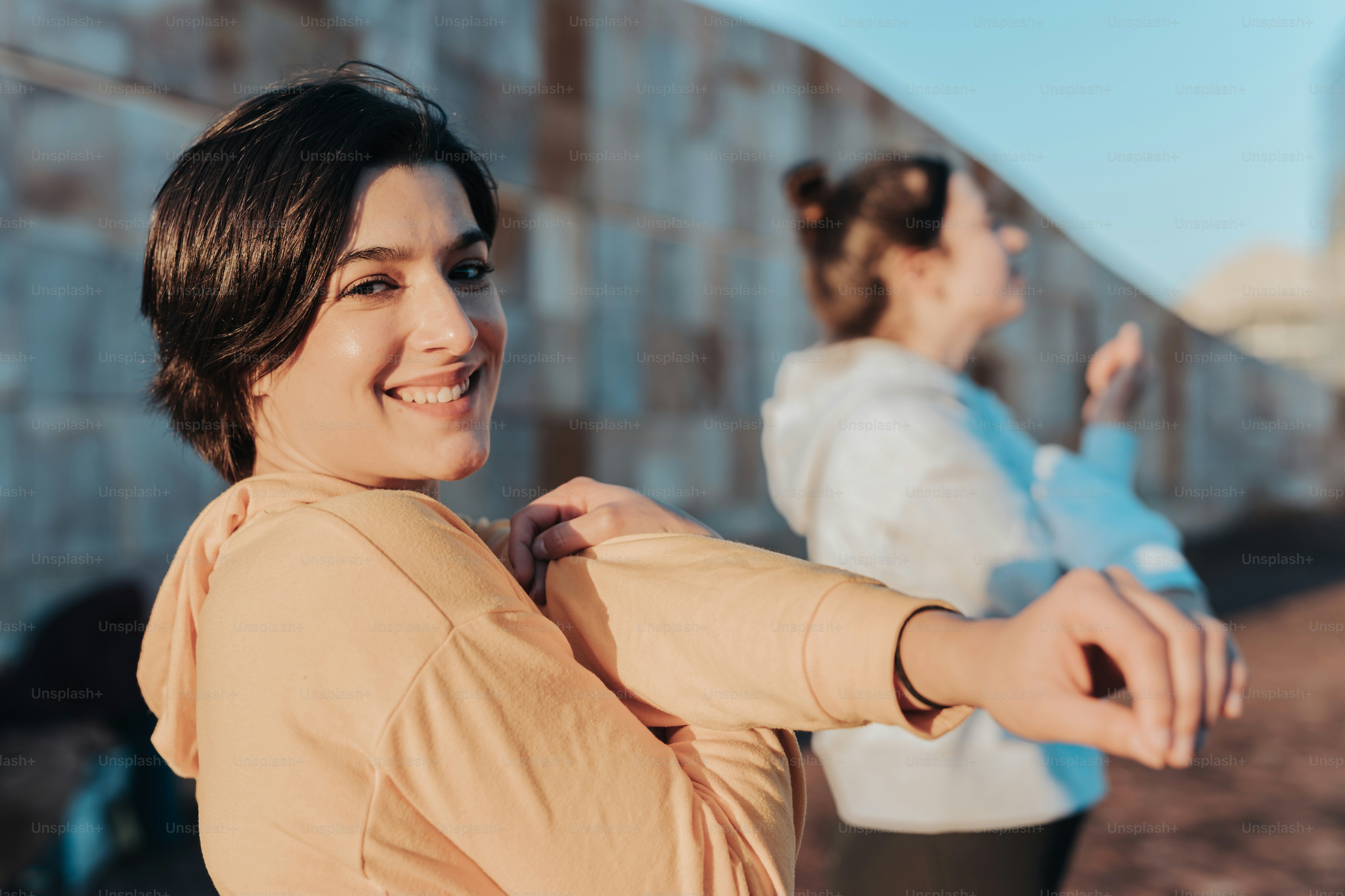 a woman standing next to another woman in front of a wall
