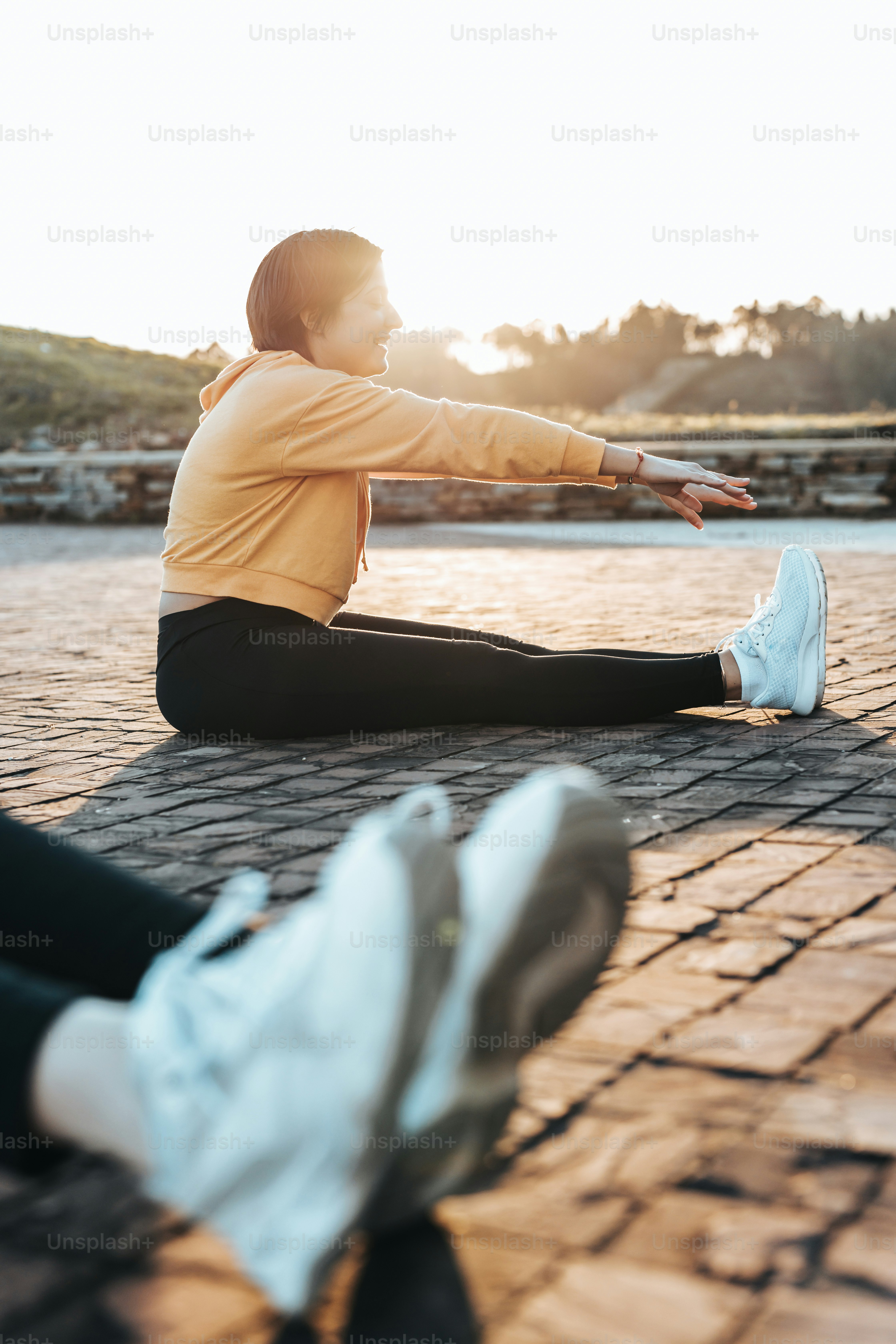 a woman sitting on the ground stretching her legs