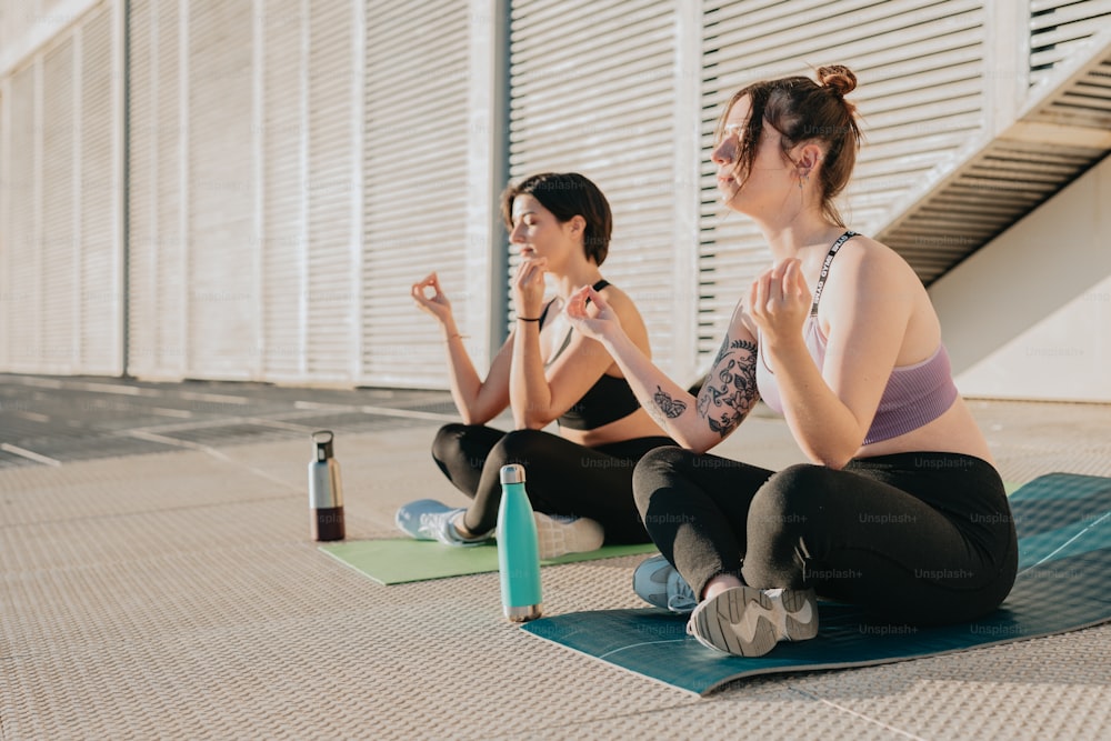 duas mulheres sentadas em tapetes de yoga fazendo exercícios de yoga