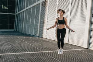 Una mujer con un sujetador deportivo y leggings está saltando en el aire