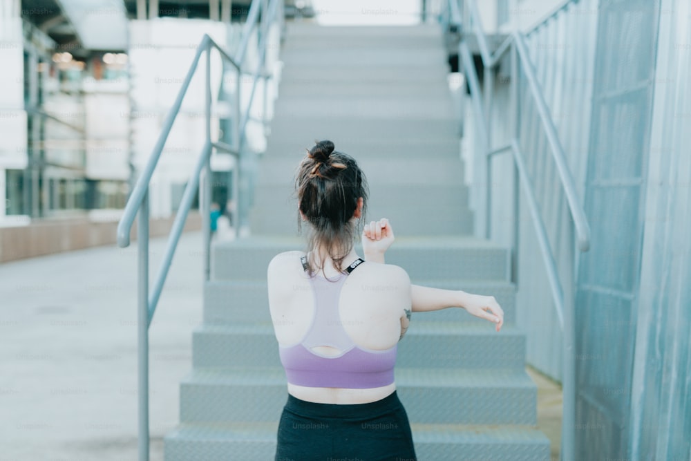 a woman in a sports bra top is walking down a flight of stairs
