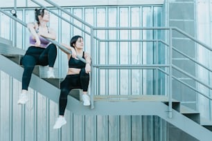 two women are sitting on the stairs of a building
