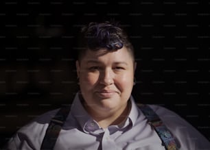 a woman with purple hair wearing suspenders and a white shirt