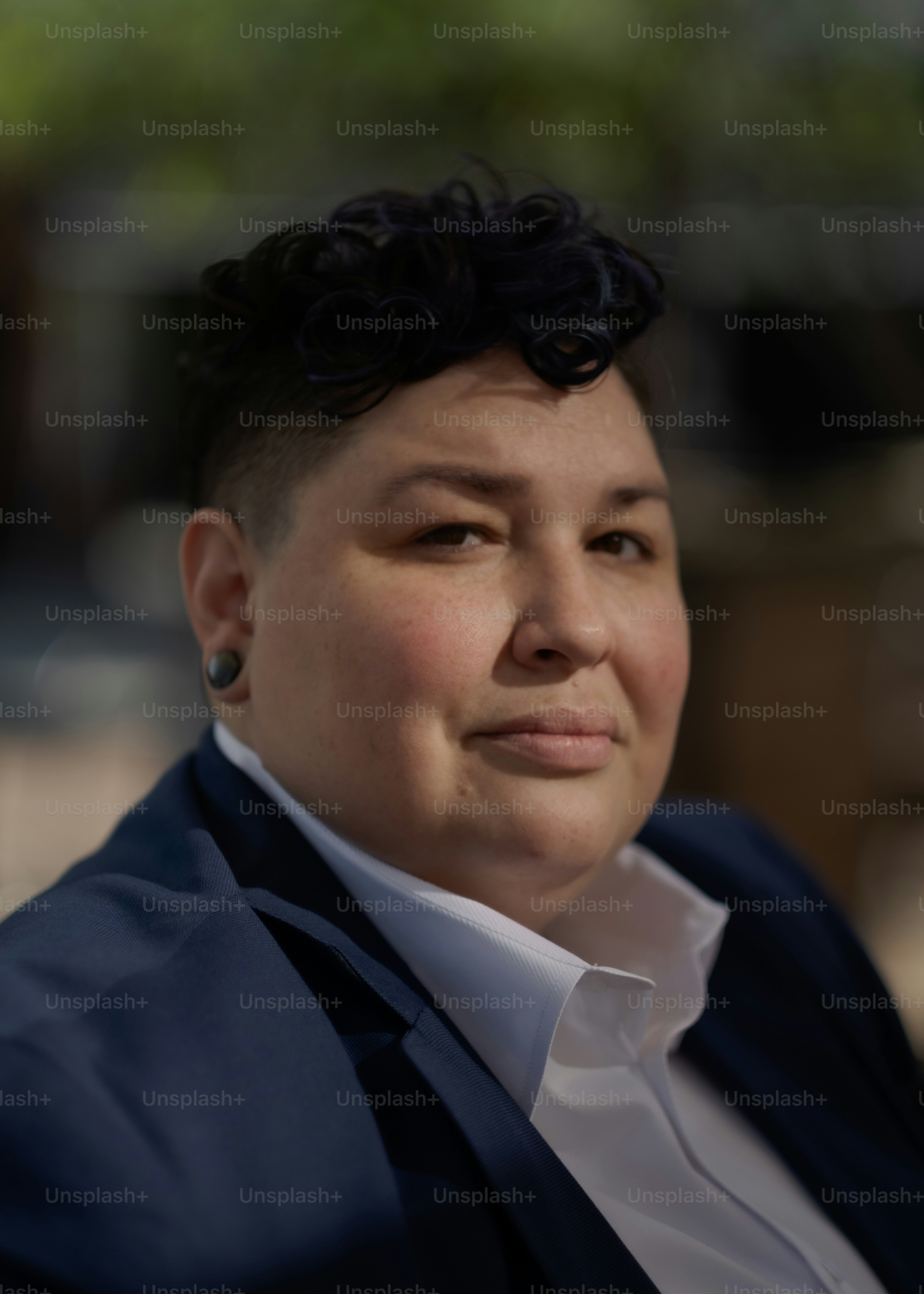 Una mujer vestida con traje y aretes mira a lo lejos