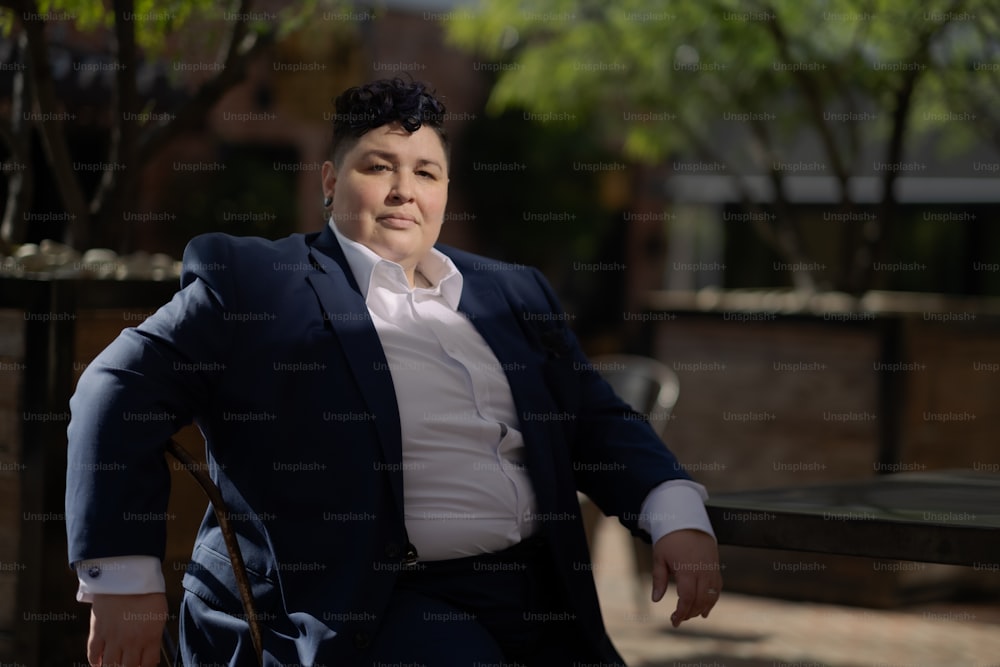Una mujer sentada en un banco con traje y corbata
