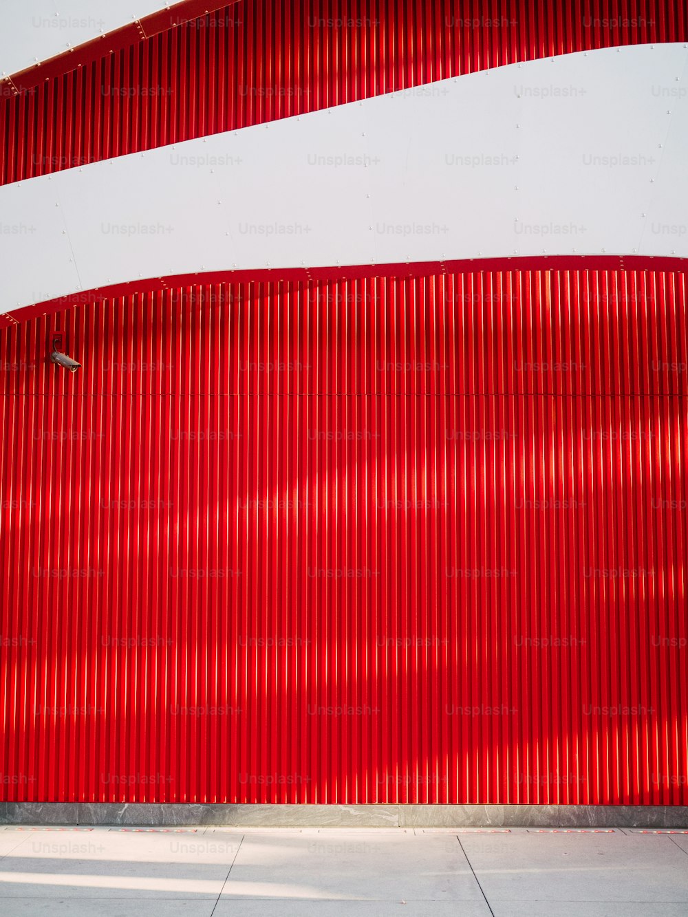 Un homme sur une planche à roulettes sur un trottoir à côté d’un mur rouge