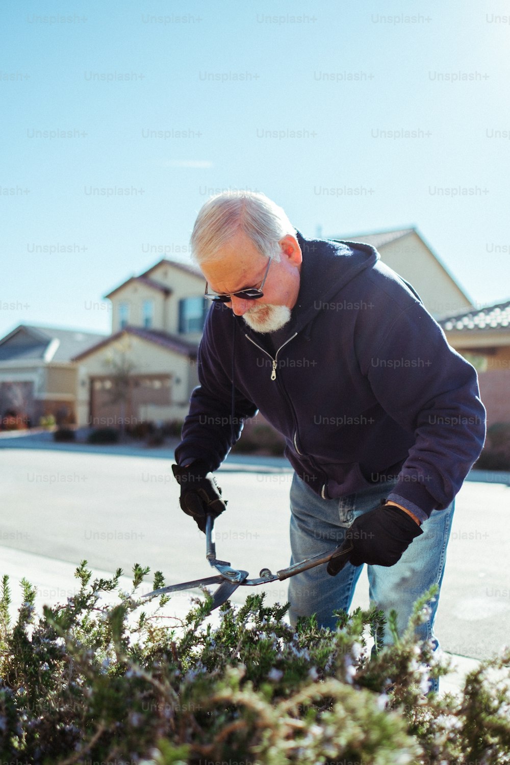 um homem cortando um arbusto com um par de tesouras