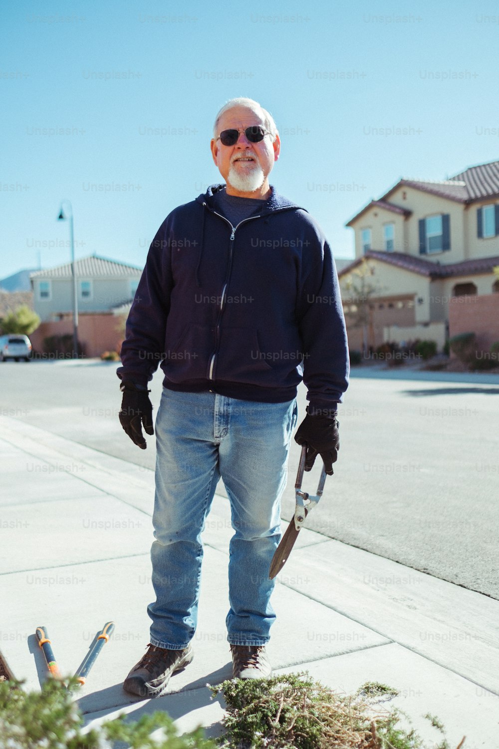 Ein Mann steht mit einer Schaufel auf einem Bürgersteig