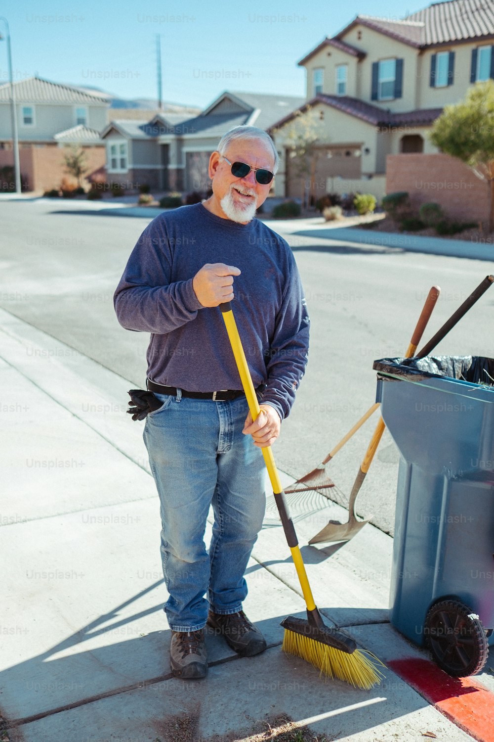 a man standing next to a trash can holding a broom