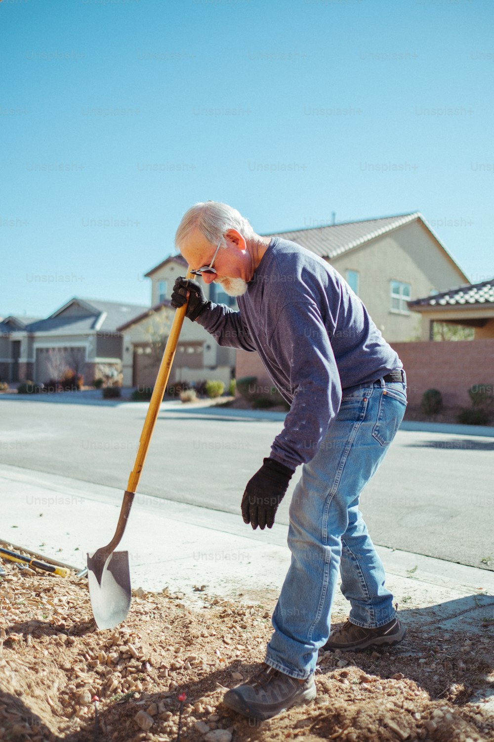a man digging dirt with a shovel on the side of the road
