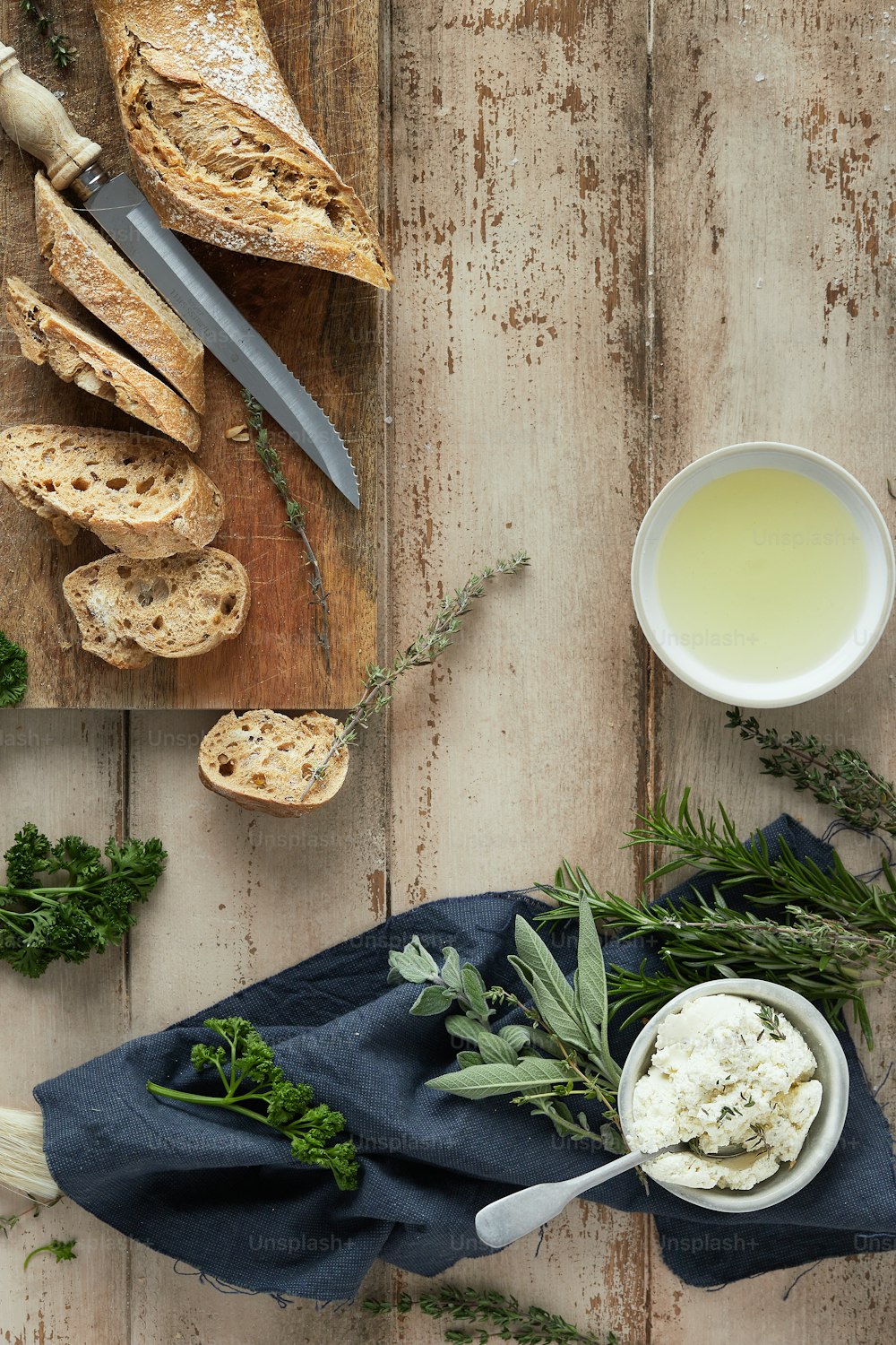 a wooden table topped with bread and a bowl of butter