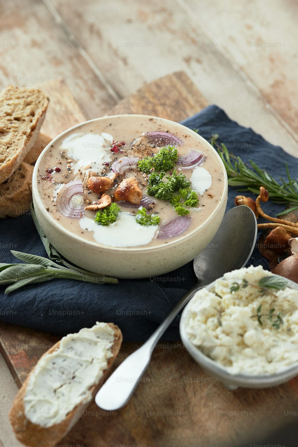 a bowl of soup on a table with bread and vegetables