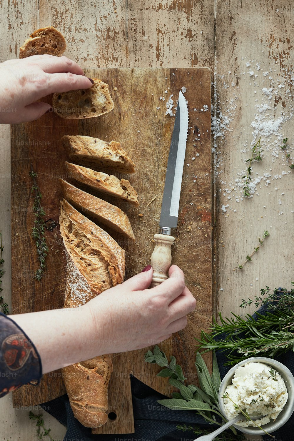 a person cutting bread with a knife on a cutting board