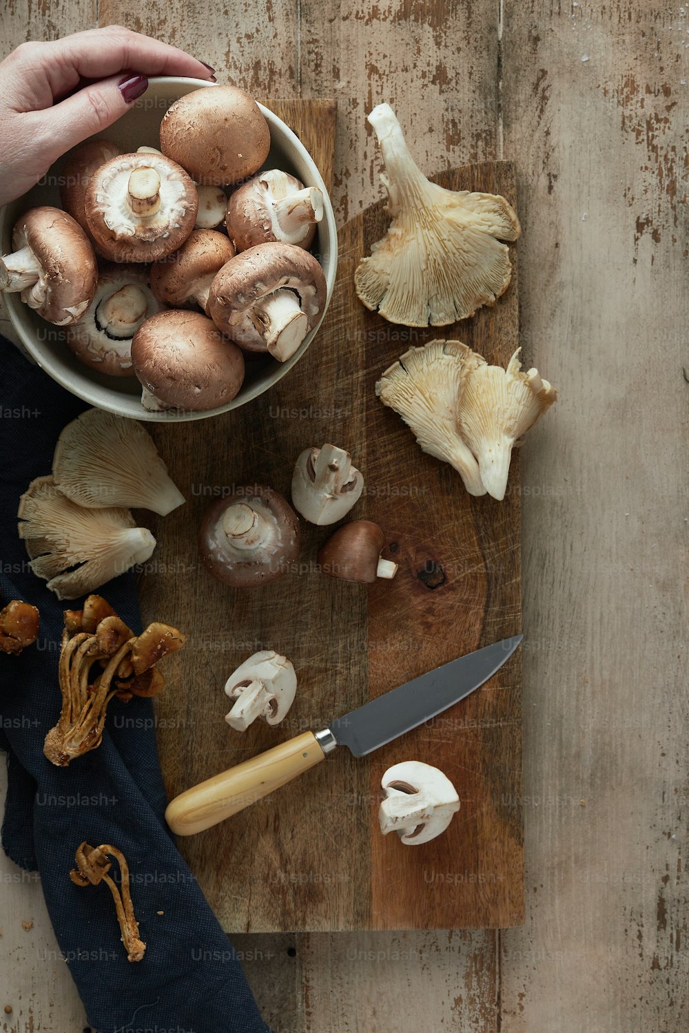 a person holding a knife over a bowl of mushrooms